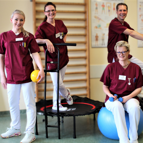 Die Abteilung Physiotherapie _drei Damen lächeln in die Kamera. Im Hntergrund sitzt Herr Neuberg, der Teamleiter auf einen Crosstrainer und lächelt ebenfalls in die Kamera.