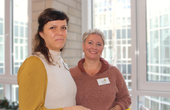 Unsere Sozialdienstmitarbeiterinnen stehen vor einer großen Fensterfassade und lächeln in die Kamera.