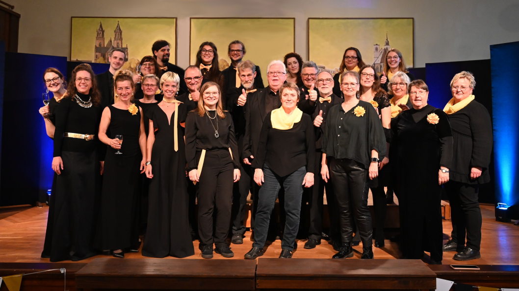 Das Gesangsensemble Multivokal mit fast 30 Sängerinnen und Sängern lächeln festlich schwarz gekleidet in die Kamera.