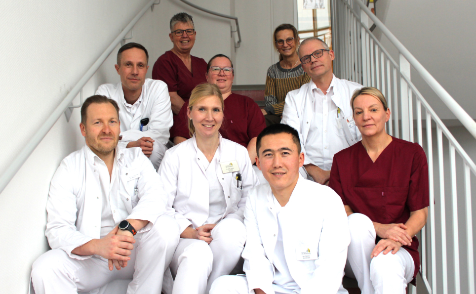 Die Kolleginnen und Kollegen der Klinik für Urologie sitzen auf einer Treppe und lächeln in die Kamera.