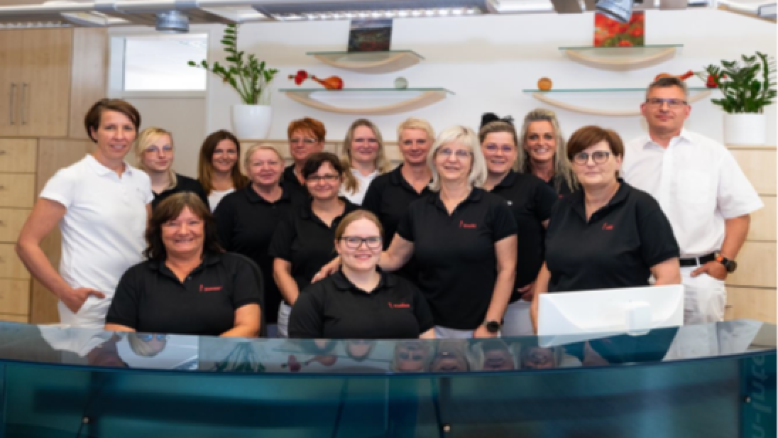 Das gesamte Team des MVZ Marienstift Burg steht hinter einem Tresen und lächelt in die Kamera.