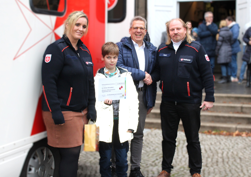 Auf dem Foto von links zu erkennen sind Mike Bleiser und Isabell Maczkowicz, die beiden ehrenamtlichen Mitarbeiter des Wärmemobils sowie der 11jährige Michel mit dem Scheck in der Hand  und Johannes Brumm, Geschäftsführer des St. Marienstiftes.
