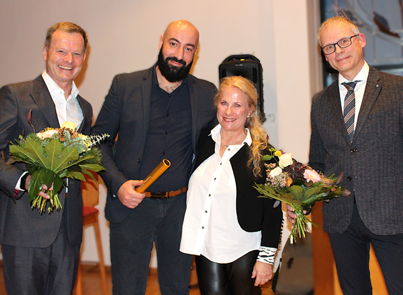 Von links nach rechts erkennen Sie Dr.  Wolfgang Hartmann, Chefarzt der Frauenheilkunde & Geburtshilfe mit einem Blumenstrauß, Khaled Benfoughal, neuer Leiter des Brustzentrums mit dem Staffelstab, Dr. Kristina Freese, die scheidende Leiterin des Brustzentrums, Dr. med. Michael Ludwig, Ärztlicher Direktor.