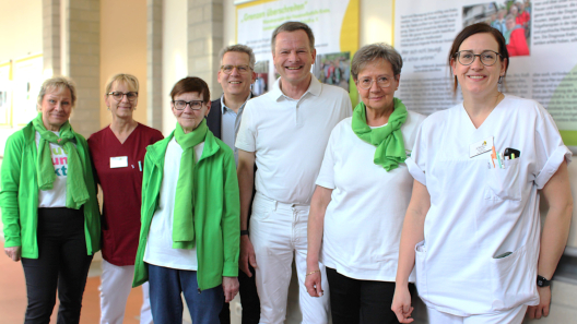 Von links nach rechts: Kerstin Seitz (Frauenselbsthilfegruppe Krebs), Katrin Hahn (Stationsverantwortliche im Brustzentrum) Hannelore Pofahl (Selbsthilfegruppe Krebs), Johannes Brumm (Geschäftsführer St. Marienstift), Dr. Wolfgang Hartmann (Chefarzt der Frauenheilkunde und Geburtshilfe), Rita Schneider (Leiterin der Frauenselbsthilfegruppe Krebs in Sachsen-Anhalt) Kristin Nüske, Fachärztin für Frauenheilkunde im Brustzentrum am St. Marienstift). Alle stehen vor einem Exponat der Ausstellung und lächeln.
